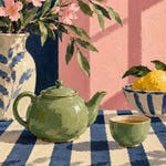 Stilleven met een groene theepot en kopje op een blauw-crème gestreept kleed, een vaas met roze bloesem en een schaal citroenen.