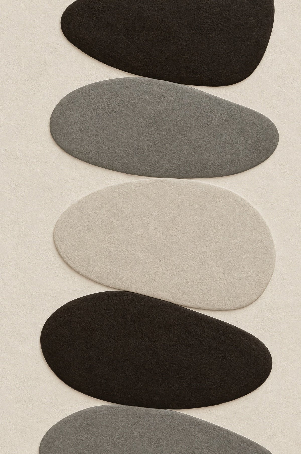 Vertical stack of pebbles in black, mineral grey and bone on an off-white ground